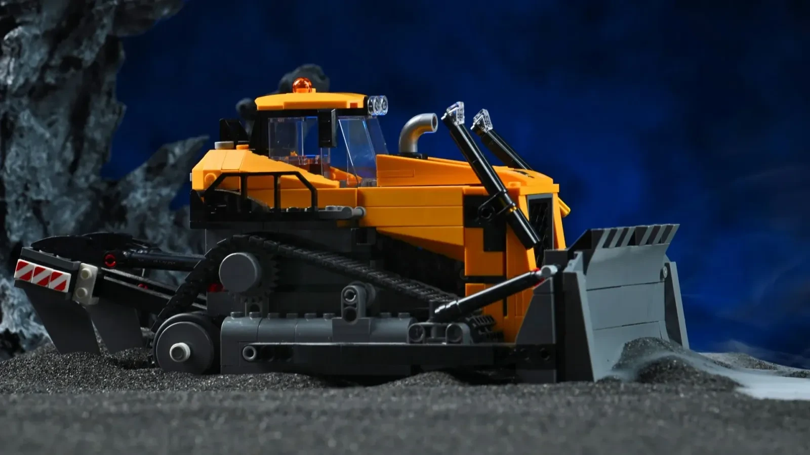 Nahaufnahme des Räumschilds und der Ketten des LEGO Gelben Bulldozers (60466), inszeniert mit Fels- und Nebelrequisiten