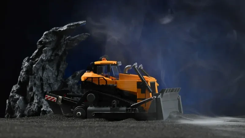 Der LEGO Gelbe Bulldozer (60466) mit angehobenem Räumschild, fotografiert auf einem Baustellen-Diorama mit Nebel und Felsrequisiten