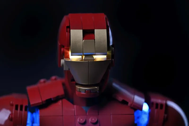 Nahaufnahme des LEGO Iron Man Mark 3 Helms mit warm goldglühenden Augen hinter der Gesichtsmaske