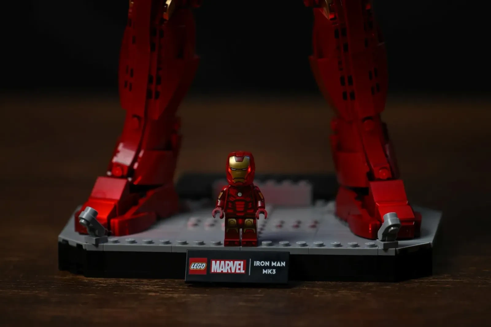 Die exklusive Iron-Man-Mark-3-Minifigur steht zwischen den Füßen der großen LEGO-Figur auf der Display-Base