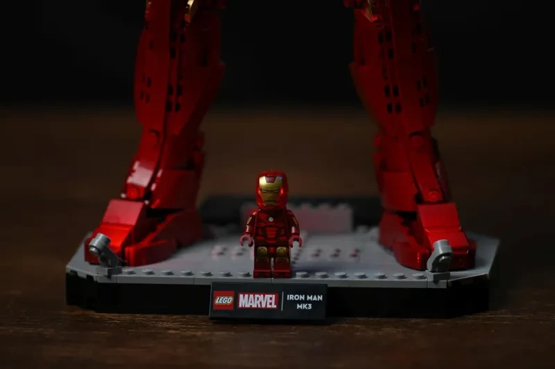 Die exklusive Iron-Man-Mark-3-Minifigur zwischen den Füßen der großen LEGO-Figur auf der Display-Base