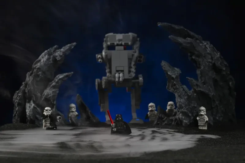 Eine LEGO-Darth-Vader-Minifigur vor einem AT-ST-Walker, mit dichtem Trockeneis-Nebel über schwarzem Boden